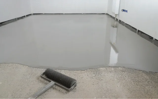 Nivelace podlahy: čerstvý samonivelační materiál s válcem.