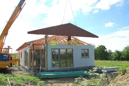 Montáž střechy na prefabrikovaný dřevěný dům pomocí kranu.