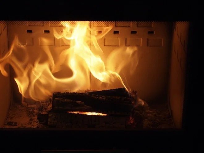Hořící dřevo v krbové vlozce s jasnými plameny.
