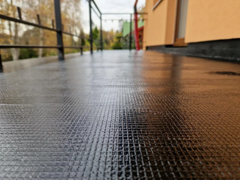 Mokrý povrch tekuté hydroizolace na střeše nebo terase.