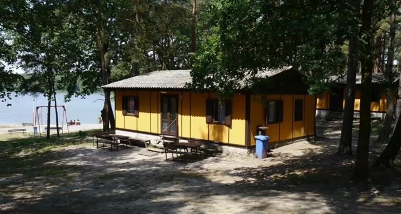 Žluté chaty v lese u jezera na kempu Holany.