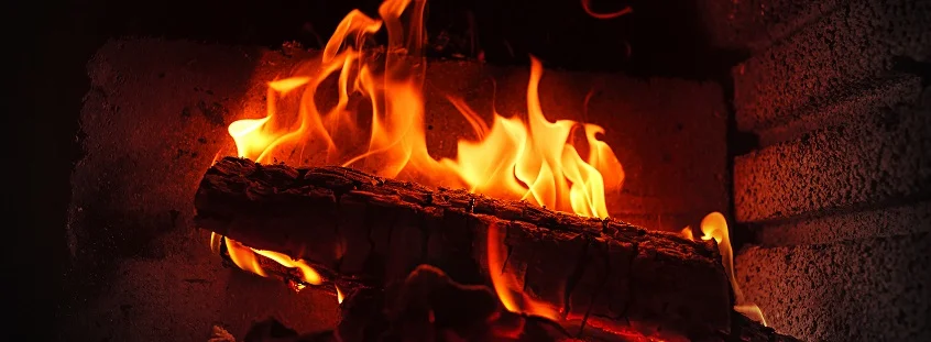Hořící dřevo v kamne s jasnými plameny pro vytápění domácnosti.