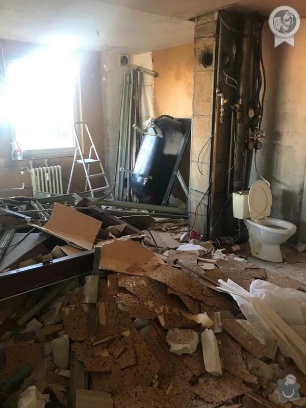 Ruiny po demolici koupelny s odhalenými potrubím.