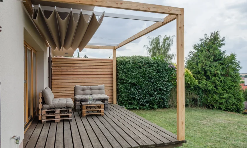 Moderní dřevěná pergola s palubovou podlahou a zahradním nábytkem.