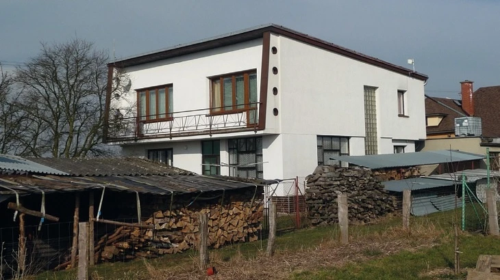 Moderní bílý dům s dřevěným ohništěm a přístřešky.