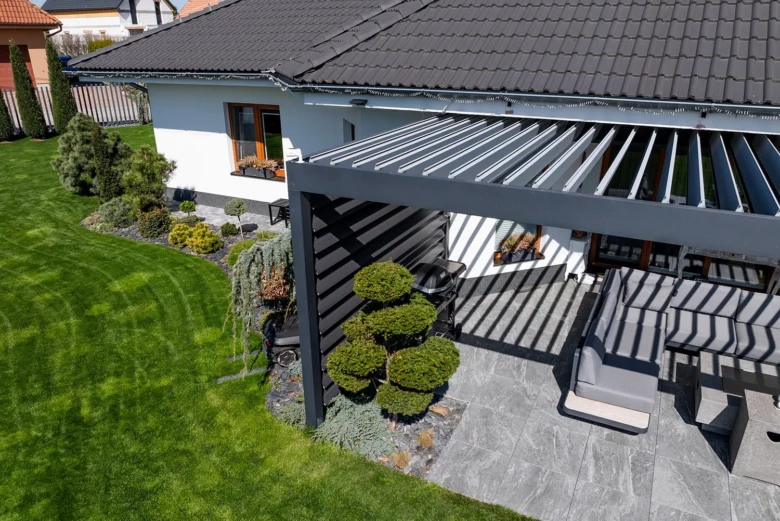 Moderní šedá pergola na zahradě u domu s venkovním posezením.