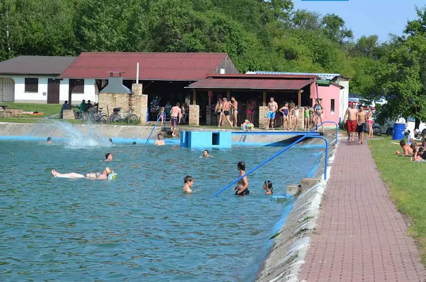 Venkovní bazén ve Všejanech s lidmi plavajícími v něm.