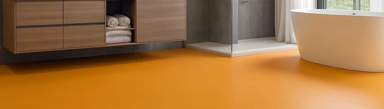Moderní koupelna s oranžovou podlahou, skříněmi a vanou.