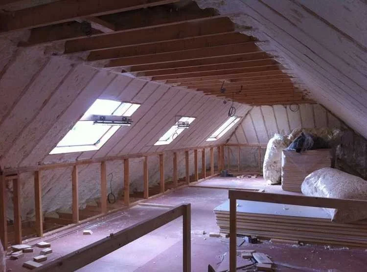 Nezhotovený strop s dřevěnými trámy a materiály na izolaci.