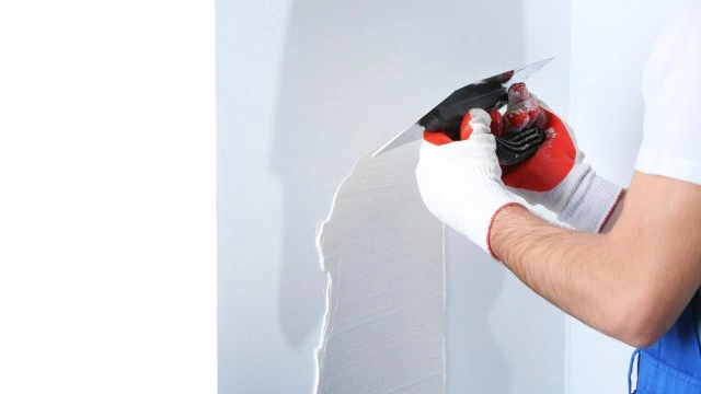 Person applying plaster to wall