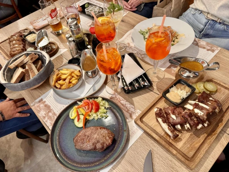 Stůl v restauraci s masem, saláty a koktejly.