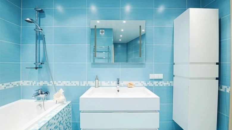 Moderní koupelna s modrými dlaždicemi, vanou a umyvadlem.