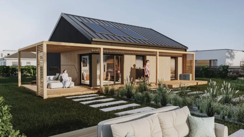 Moderní prefabrikovaný dřevěný dům s solárními panely a zahradním posezením.