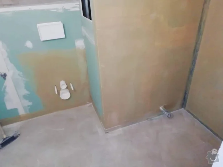 Přestavba koupelny s viditelnými instalačními prvky a omítkou.