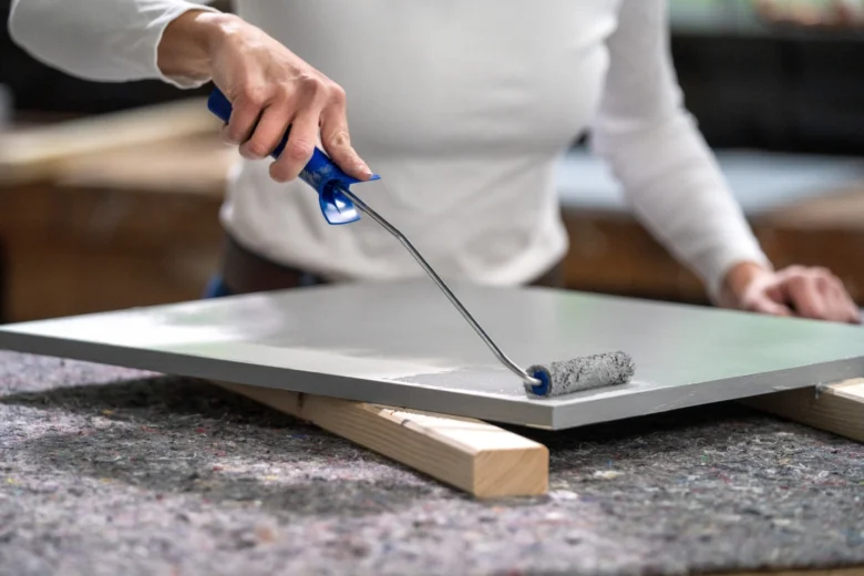 Osoba maluje desku válečkem při renovaci kuchyně.