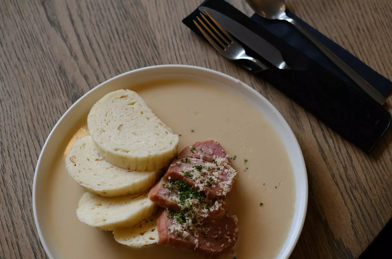 Bílá miska s krémovou polévkou, masem a chlebem.