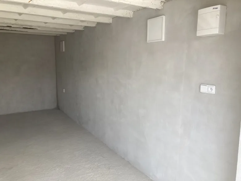 Průhled do místnosti s hotovou jádrovou omítkou na stěnách a podlaze.