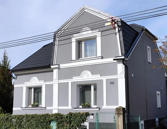 Modernizovaná fasáda domu po rekonstrukci s bílým lemováním.