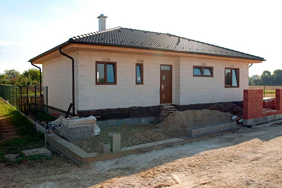 Rodinný dům z porobetonu ve fázi dokončování s okny a střechou.