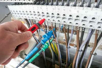 Ruční testovací nástroj pro revizi elektrické instalace v rozvaděči.