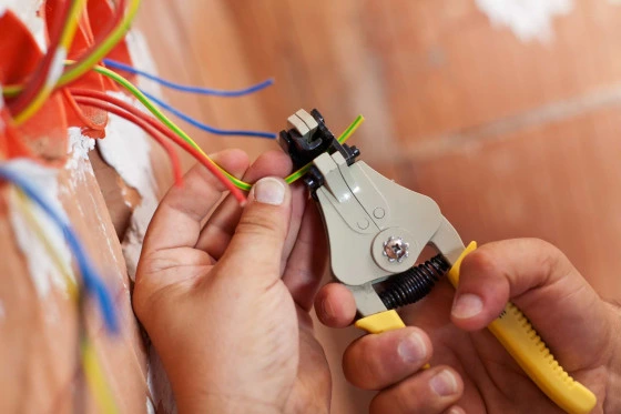 Elektroinženýr připravuje barevné vodiče pro označení fází v instalaci.