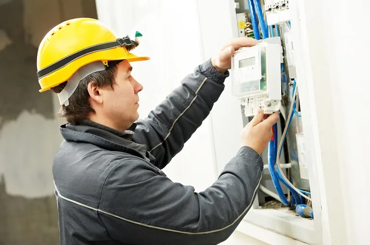 Elektrikář upravuje elektroměrový rozvaděč s viditelným zapojením.