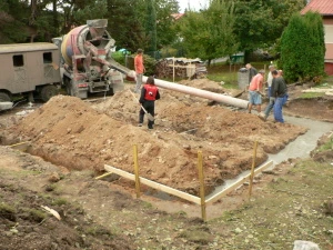 Stavební dělníci nalévají beton do základů domu v Praze.