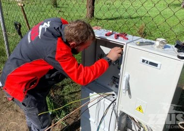 Elektrikář pracuje na zapojení elektroměrového rozvaděče venku.