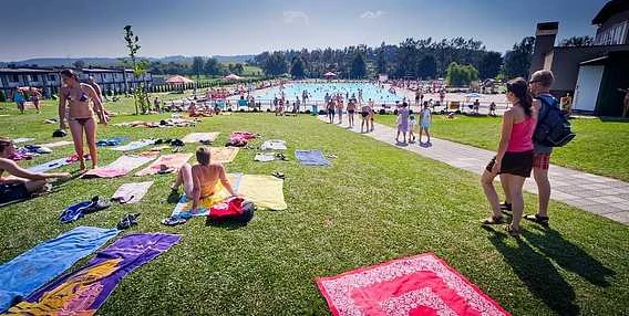 Lidé u venkovního bazénu v Dobrušce na slunečním dni.