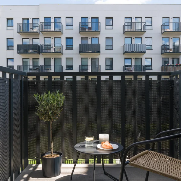 Moderní balkon s nábytkem před bytovou výškovkou.