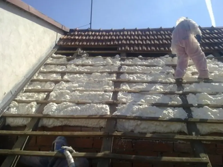 Montáž izolační pěny na střeše mezi trámy.
