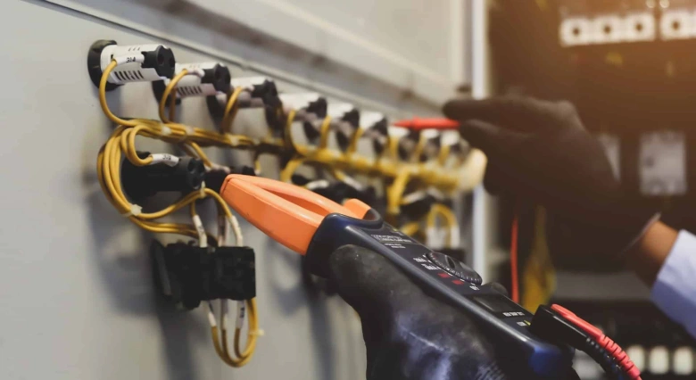 Elektroinženýr měří napětí v rozvaděči multimetrem.