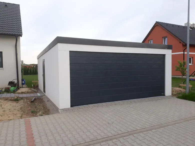 Moderní samostatná garáž s velkým otevíracím dveřmi pro auto.