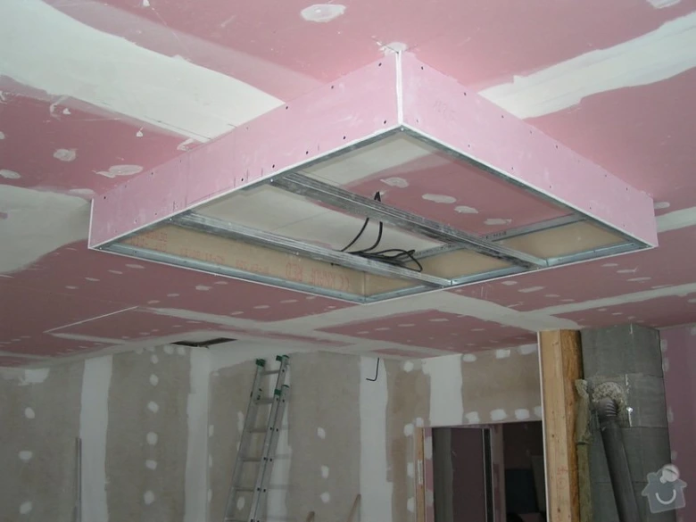 Instalace sádrokartonu na stropě v průběhu stavby.