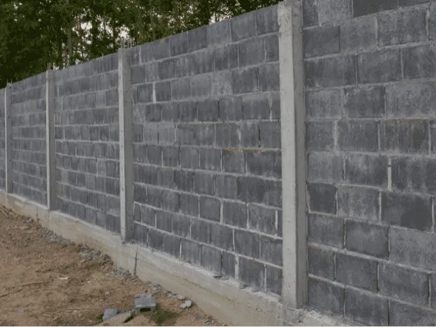 Nová betonová zeď z cihlových bloků s betonnými sloupky.
