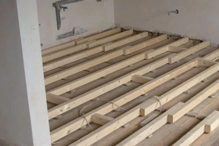 Dřevěné trámy pro podlahu v rekonstruované místnosti.