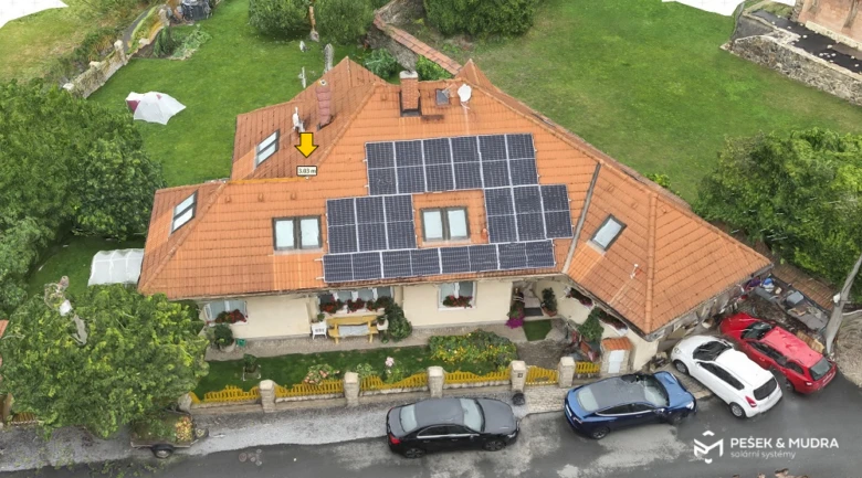 Fotovoltaické panely na střeše rodinného domu s parkovanými auty