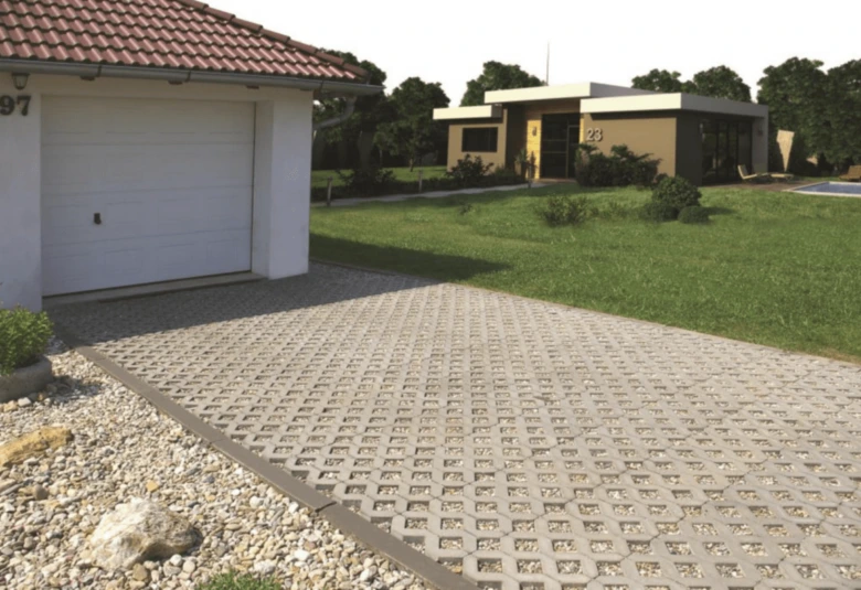 Zatravňovací dlažba s betonovými kostky na parkovišti domu.