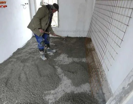 Stavebník nalévá betonovou podlahu do připraveného prostoru.