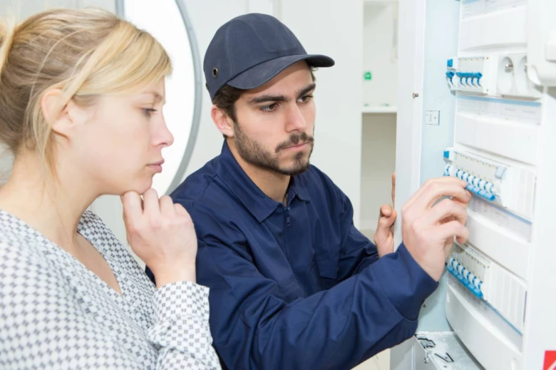 Elektrikář kontroluje jističe v rozvaděči pro elektroinstalaci.