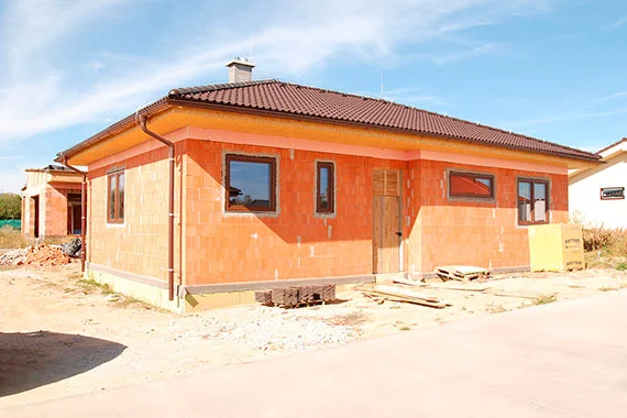Rodinný dům z porobetonu ve fázi stavby s viditelnými okny.