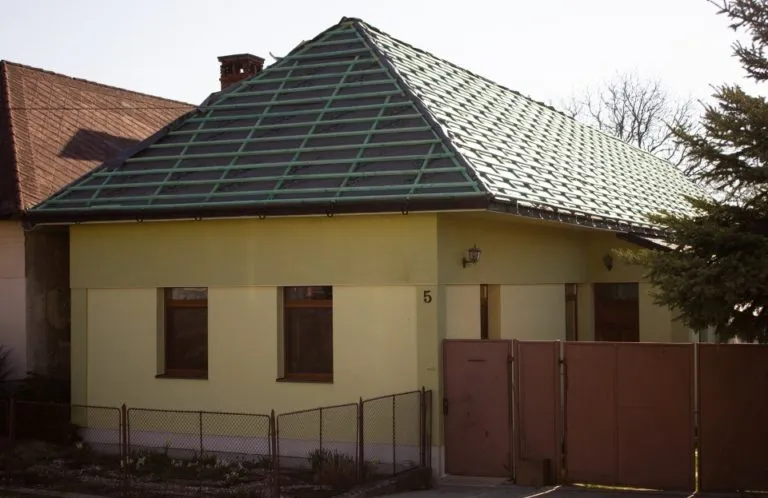 Fotografie vazníkové střechy s viditelnými střešními vazni na žlutém domě.