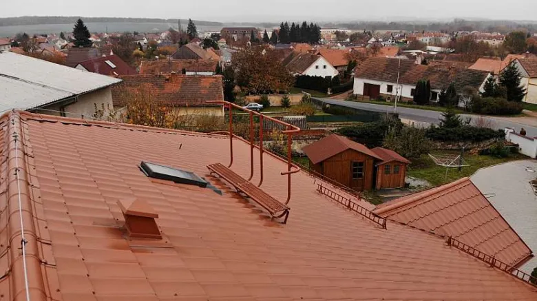 Instalace komínové lávky se střešním nášlapem na červené taškové střechě.