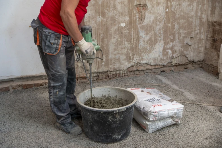 Stavebník míchá lehčený beton v kbelíku s motorem.