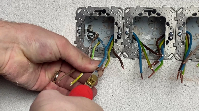 Ruční zapojení vypínače s vodiči v elektrickém rozvaděči.