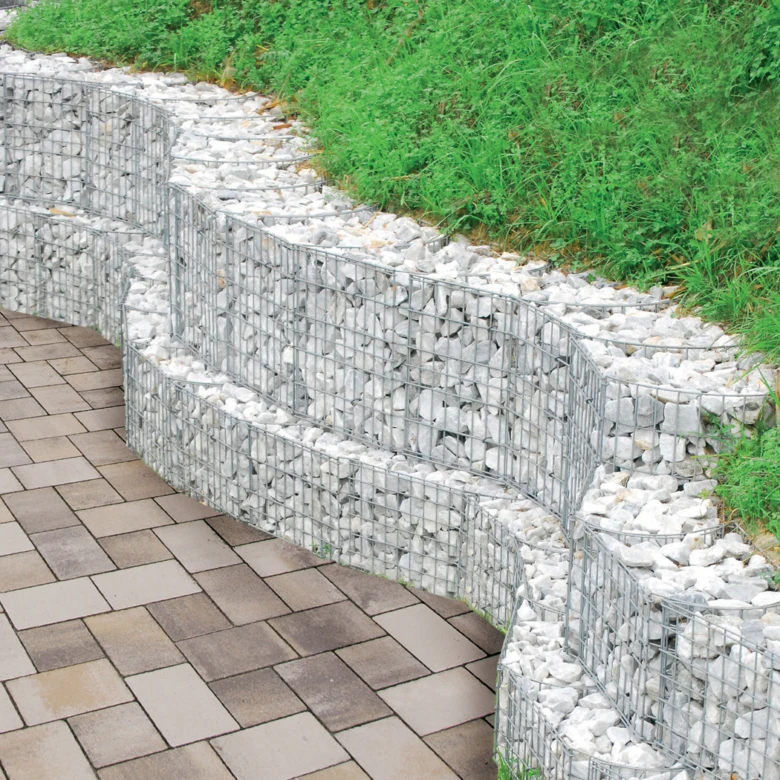 Křivá palisáda z koryt s kamenem stabilizující svah zahrady.