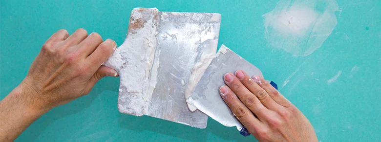 Hands applying plaster with trowel