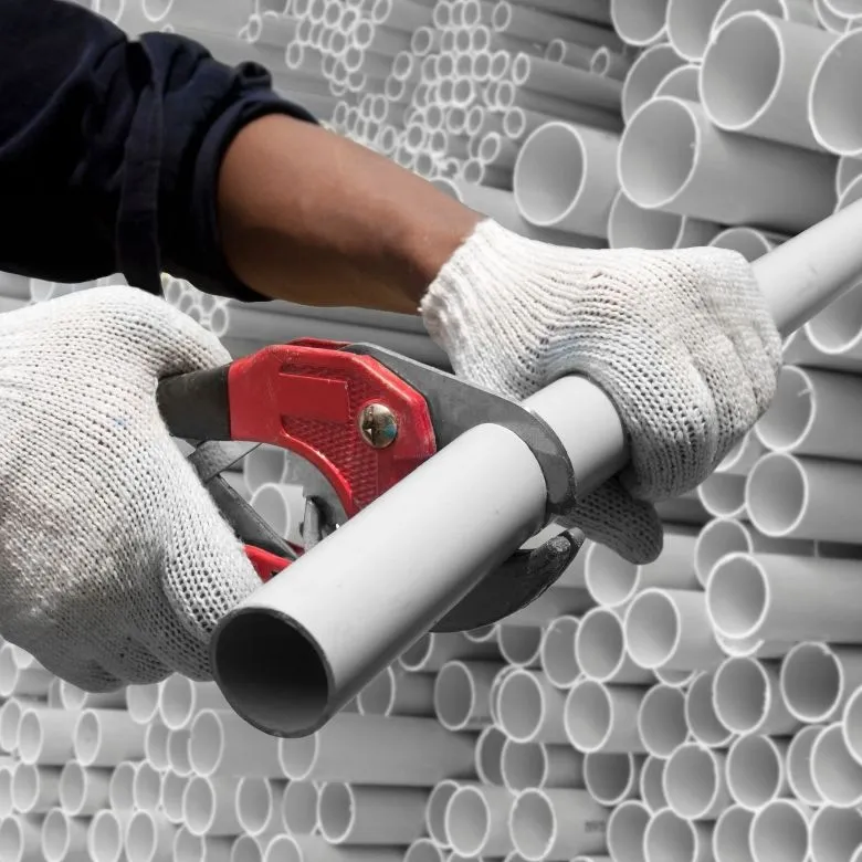 Průřez bílého PVC potrubí pro elektroinstalaci rukavicemi.