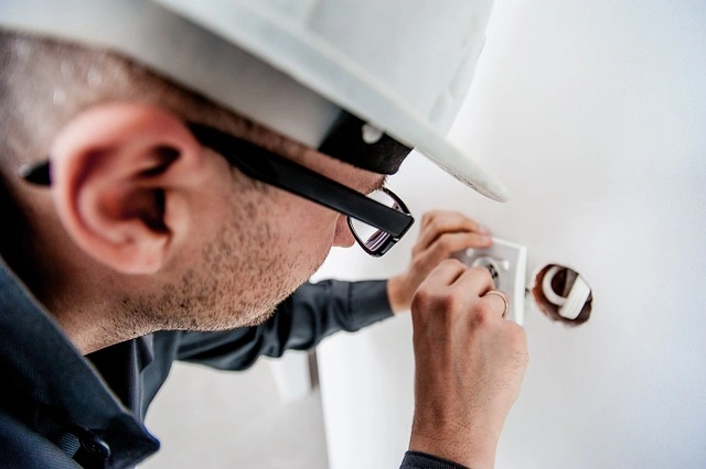 Elektrikář montuje zásuvku v elektrické instalaci.
