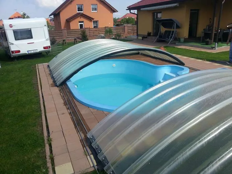 Modulární střecha pro bazén s průhledným krytem na kolejnicích.